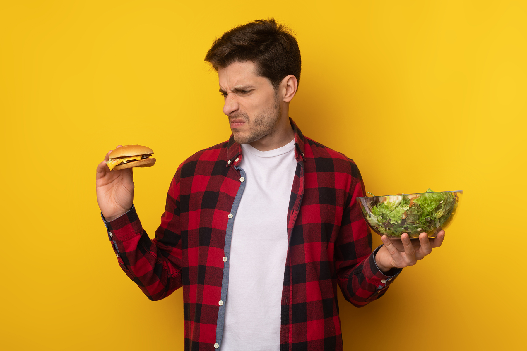 Portrait of Funny Guy Holding Burger And Vegetable Salad